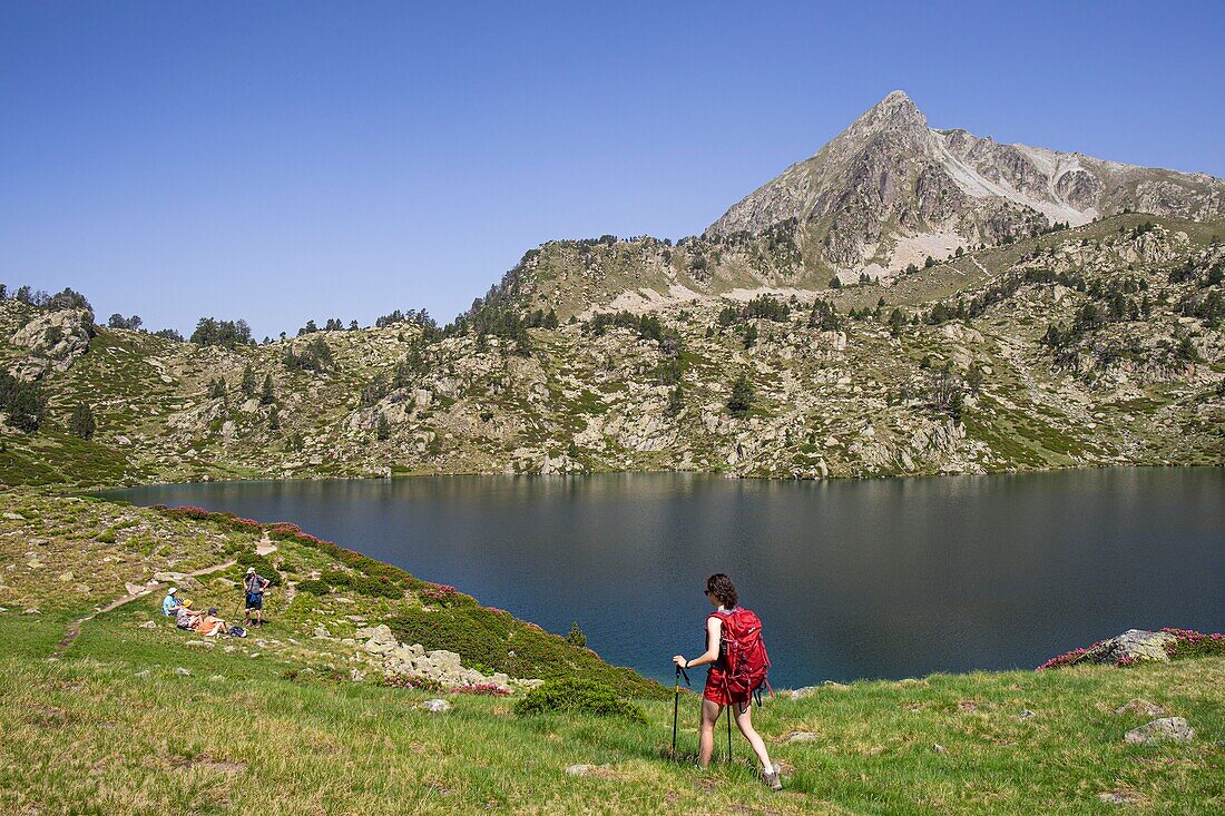 France, Hautes Pyrenees, upper lake of Bastan and peak of Bastan (2724m), hiker walking along the upper lake of Bastan\n