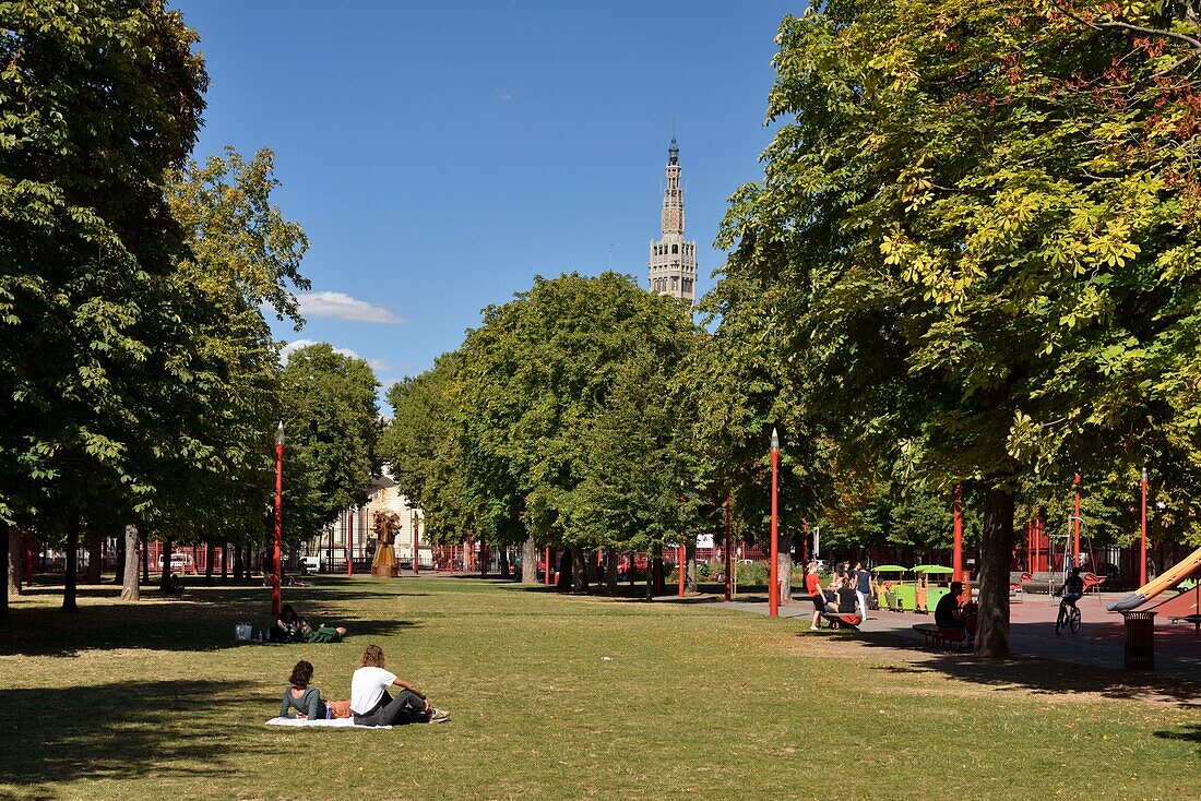France, Nord, Lille, Jean Baptiste Lebas park with characteristic red grilles dominated by the belfry listed as World Heritage by UNESCO and which houses the services of the town hall, couple on the grass\n