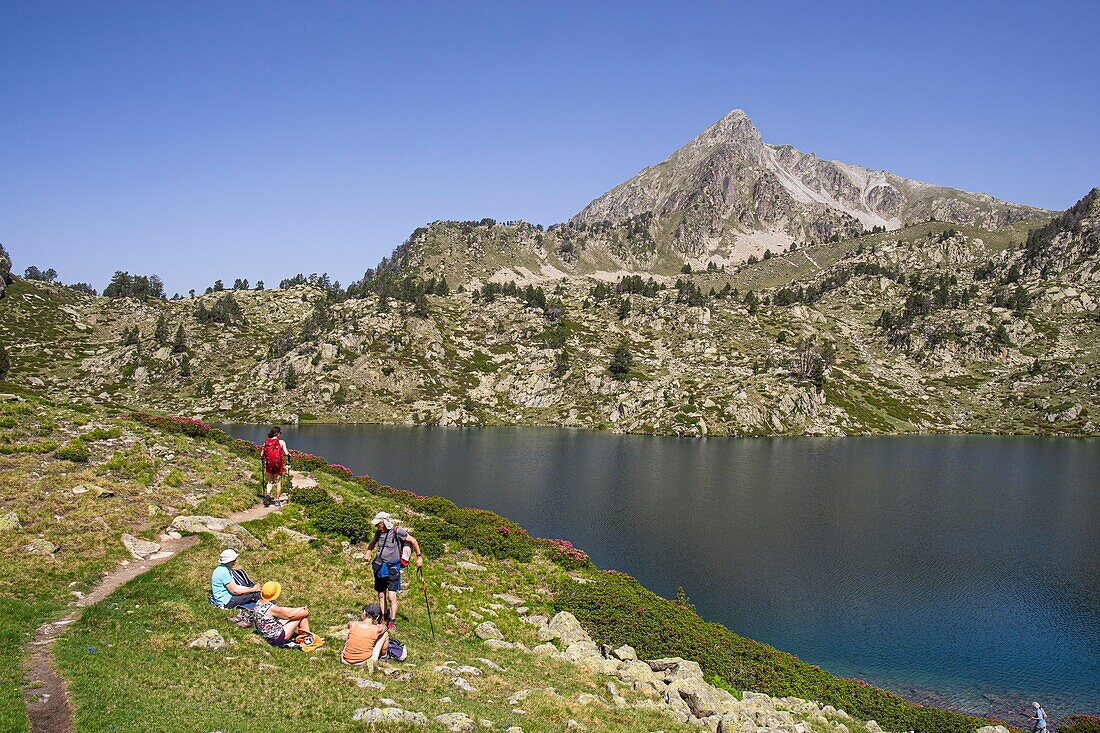 France, Hautes Pyrenees, upper lake of Bastan and peak of Bastan ( 2724m ), hikers on the edge of the upper lake of Bastan\n