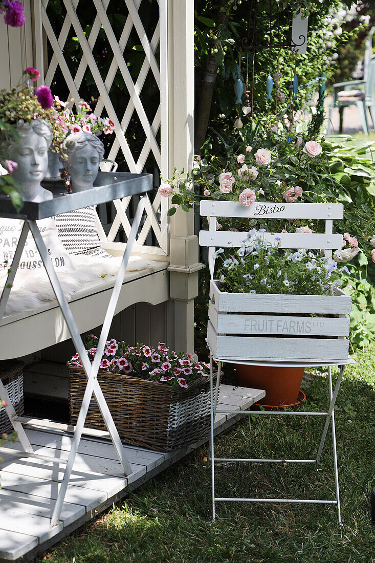 Philosopher's bench with decorated table and garden chair, busts, horned violets, rose trees