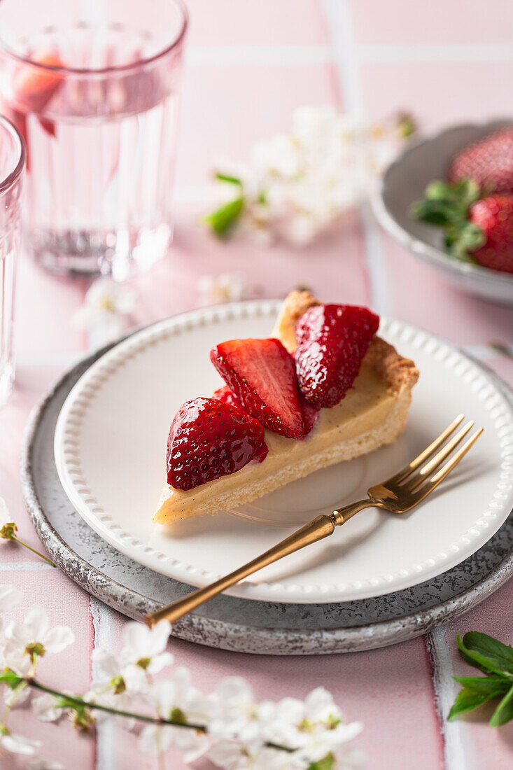 A slice of custard tart with fresh strawberries