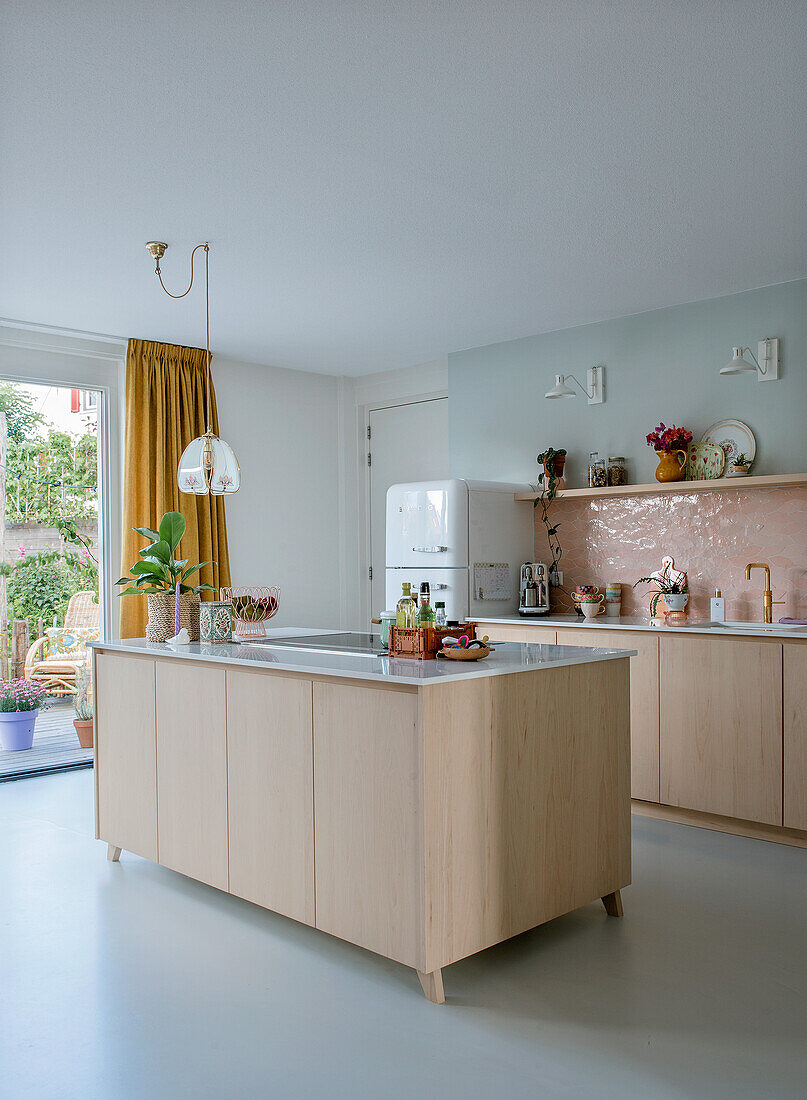 Bright kitchen with light wood island, retro fridge and ochre yellow curtains