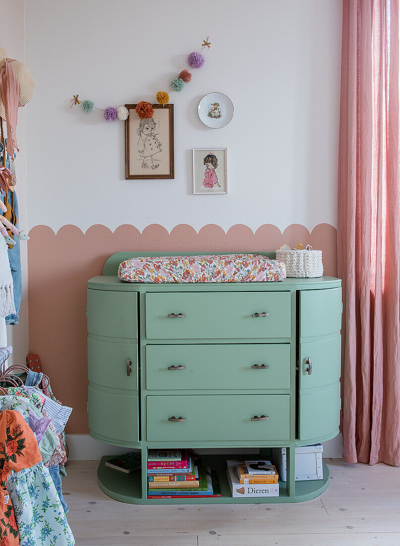 Mintfarbene Wickelkommode mit Blumenmotiv-Wickelauflage und Wanddeko im Kinderzimmer