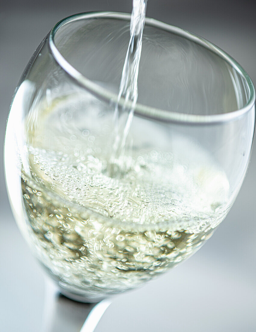 Weißwein in ein Glas schütten