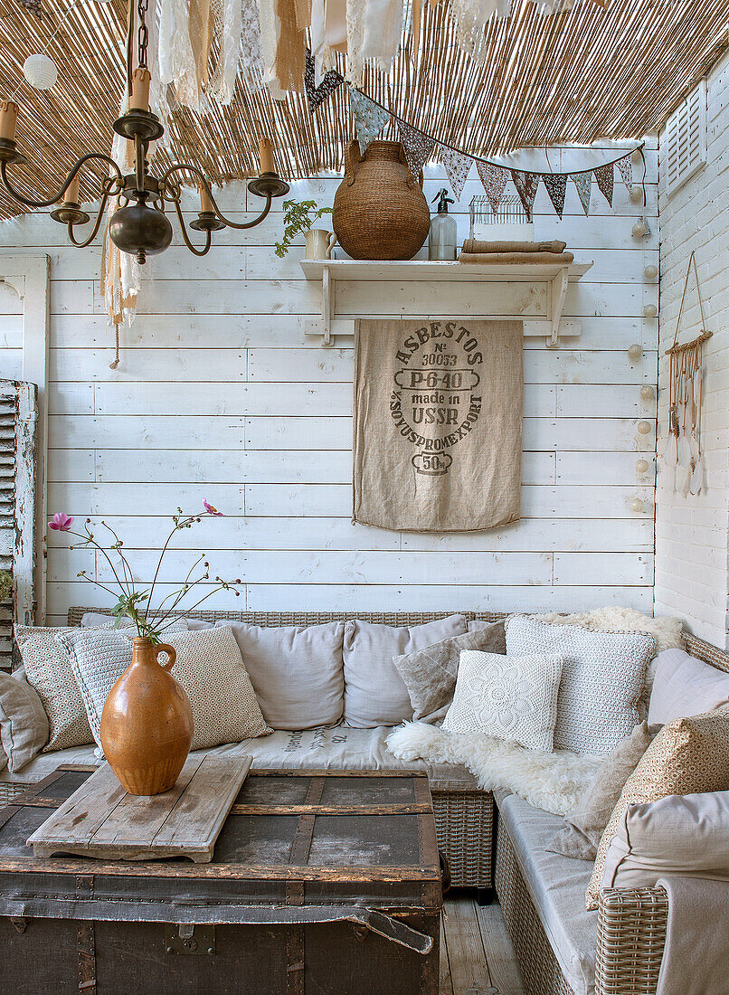 Überdachte Terrasse mit Rattansofa und Vintage-Deko