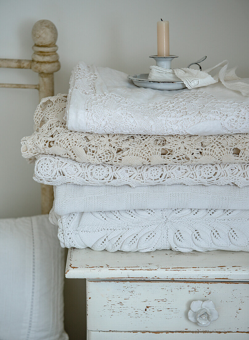 Crocheted blankets and candle holders on an antique bedside table