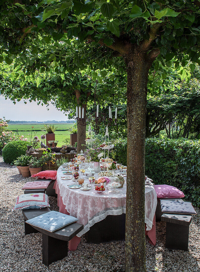 Geschmückter Gartentisch unter Bäumen für eine sommerliche Kaffeetafel