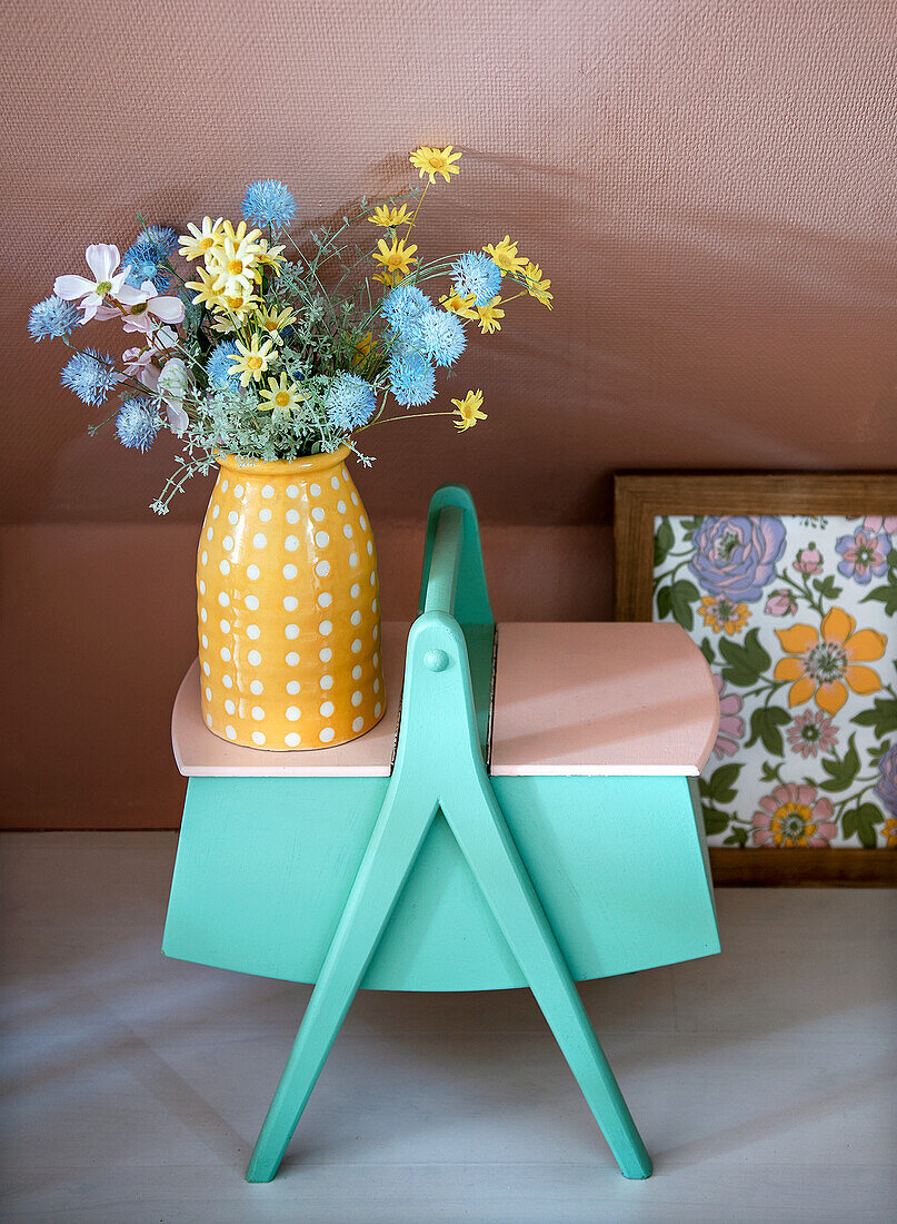 Flowers in a yellow vase with white dots on a painted vintage sewing box