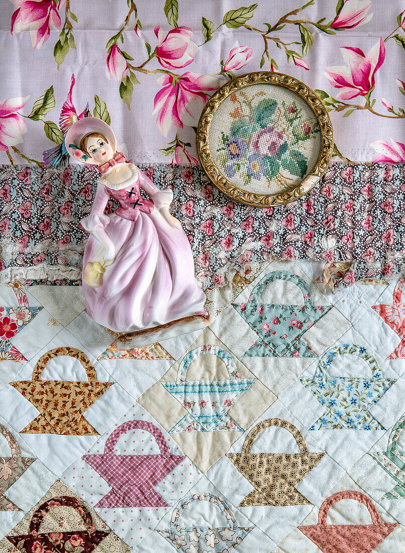 Quilt with basket pattern, porcelain figurine and framed embroidered picture