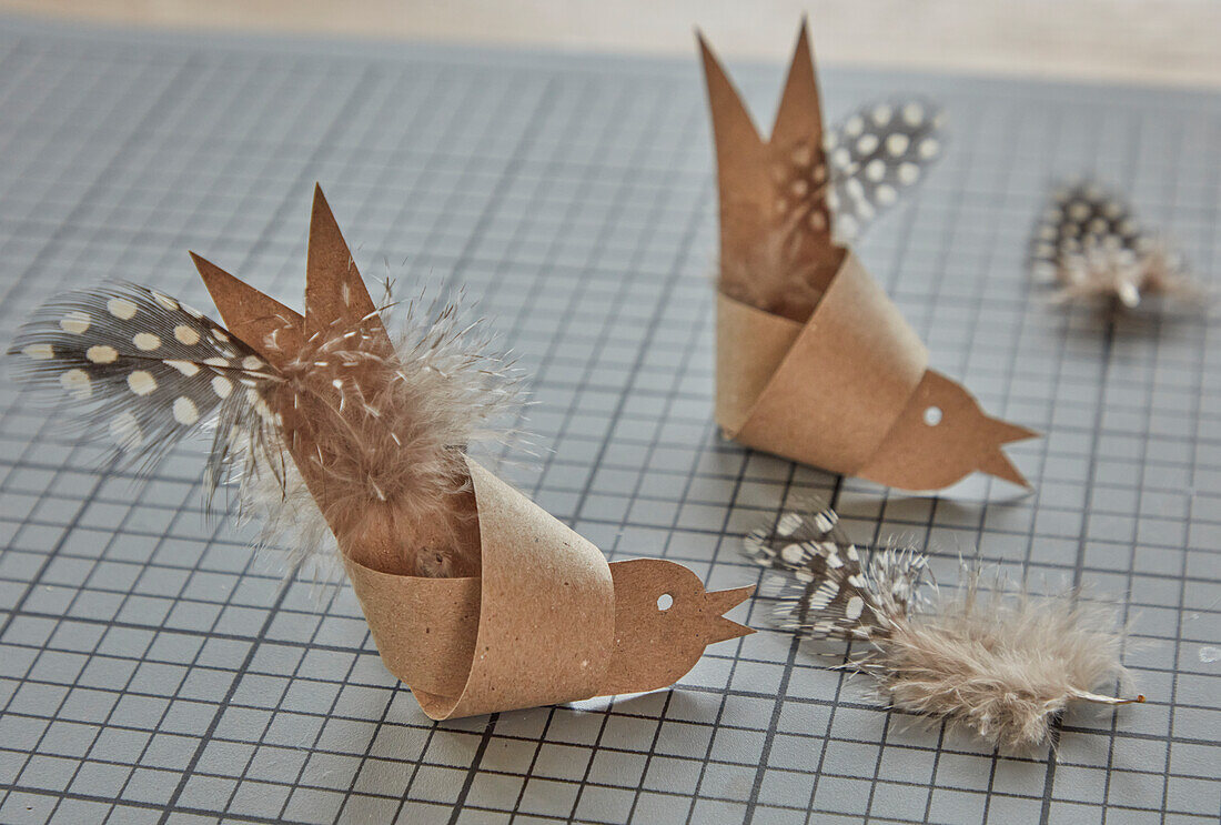 DIY-Vogel aus braunem Papier mit gepunkteten Federn auf Schneidematte