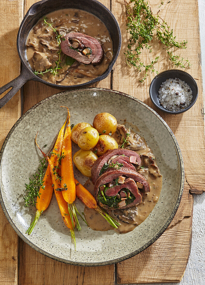 Stuffed roast venison with mushroom sauce, carrots and potatoes