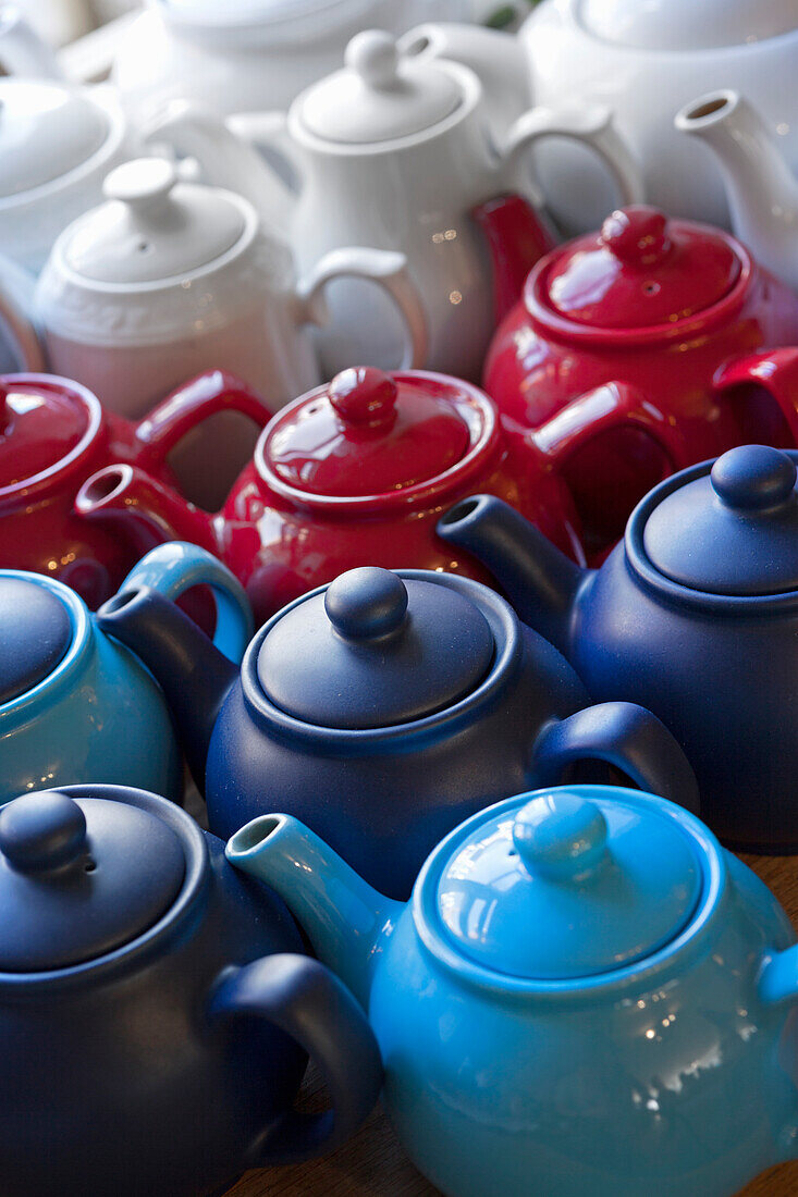 Various teapots lined up in shades of blue, red and white