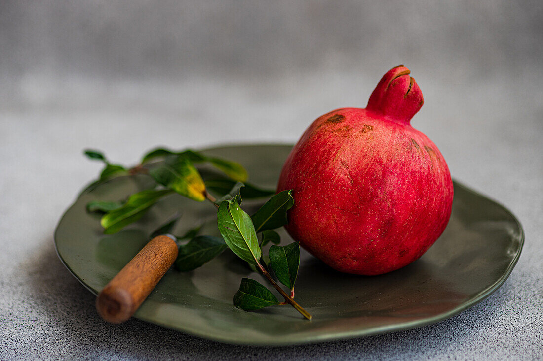 Ripe pomegranate with leaves on a plate