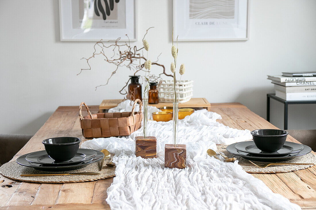 Wooden dining room table setting with black crockery and Scandinavian decoration