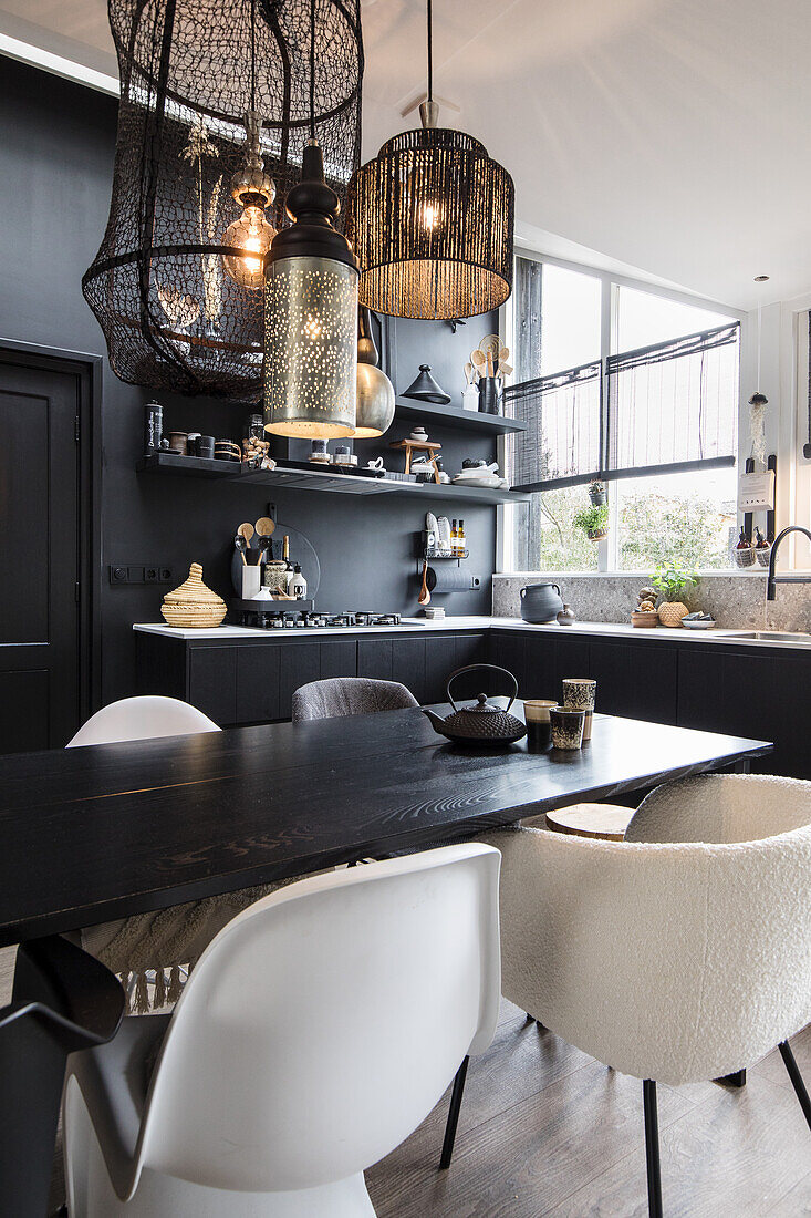 Black and white kitchen with designer pendant lights and various chairs