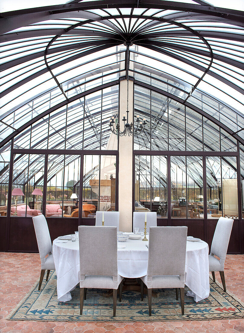 Festlich gedeckter Tisch in elegantem Wintergarten mit Glasdach und Kronleuchter