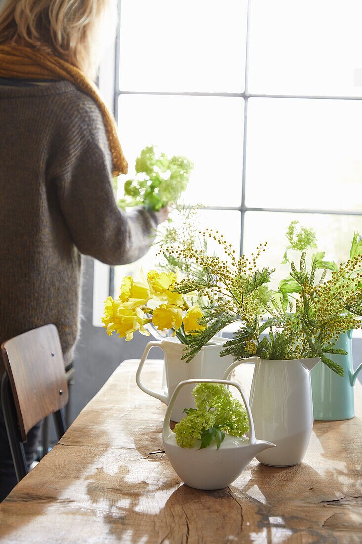 Teapot with snowball (viburnum) and spring bouquets in vases on dining table