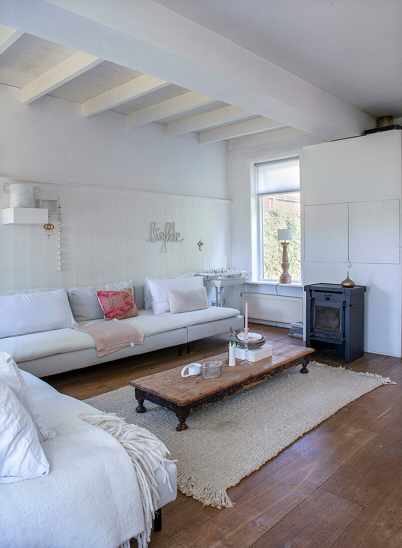 Bright living room with wood-burning stove, wooden ceiling and low wooden table on carpet