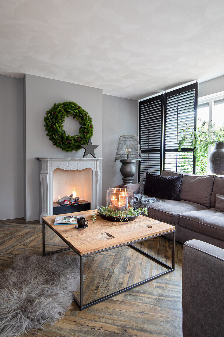 Living room with fireplace, grey corner sofa and wooden table on a herringbone parquet floor