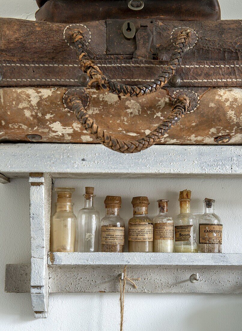 Antique suitcases and vintage pharmacy bottles on a wooden shelf