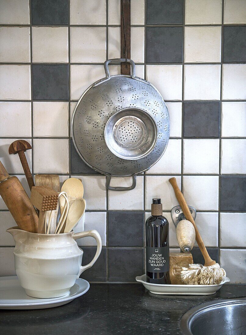 Kitchen scene with rustic utensils in front of checkered tiles