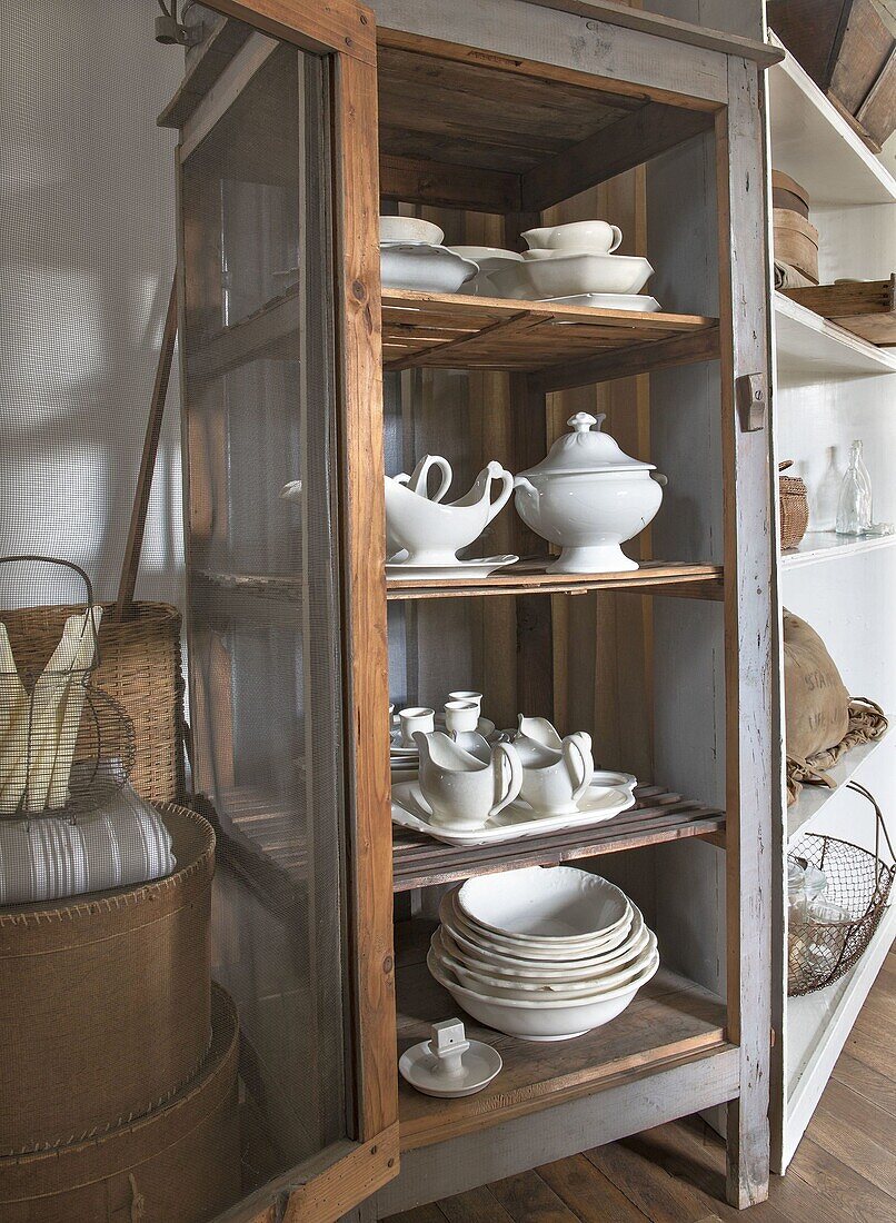 Vintage-Vitrinenschrank mit weißem Porzellanservice im Landhausstil