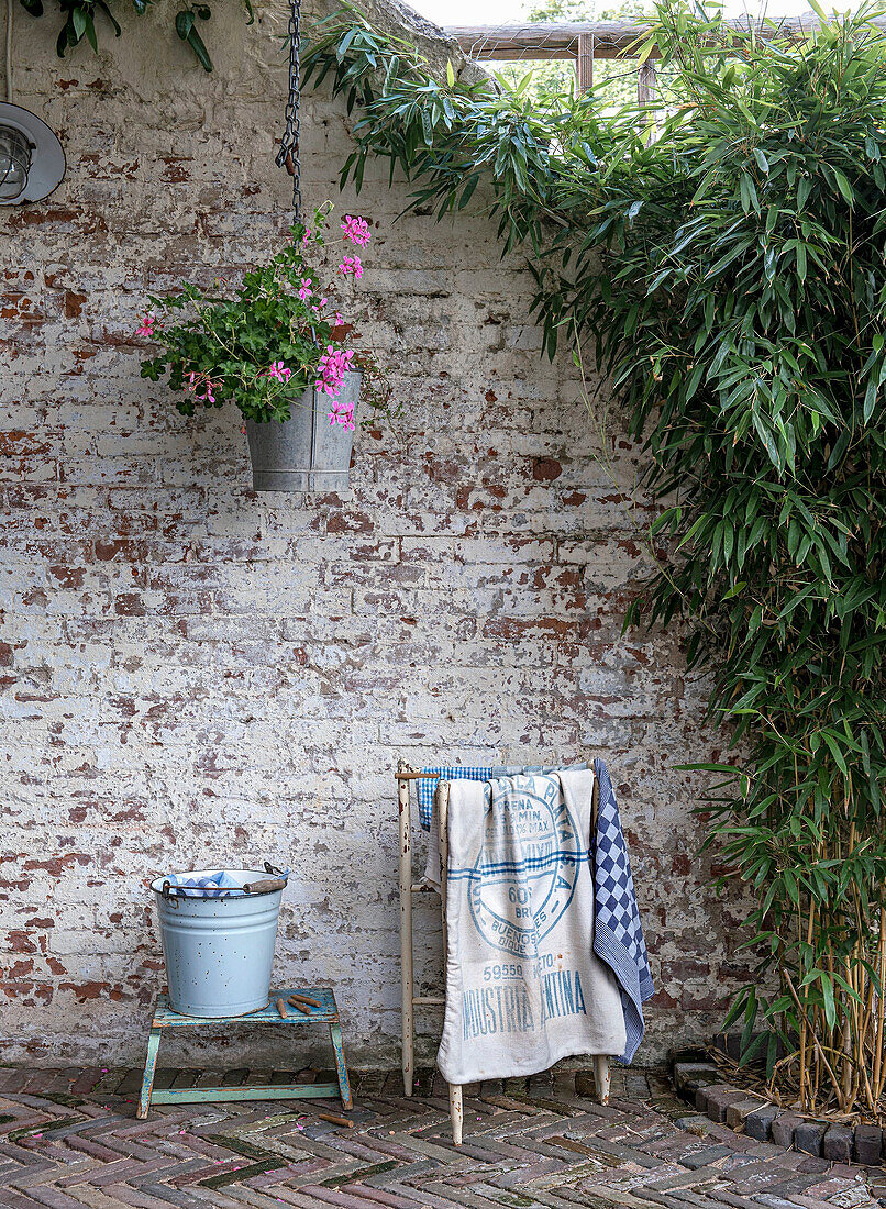 Rustic garden corner with hanging flower pot and old brick wall