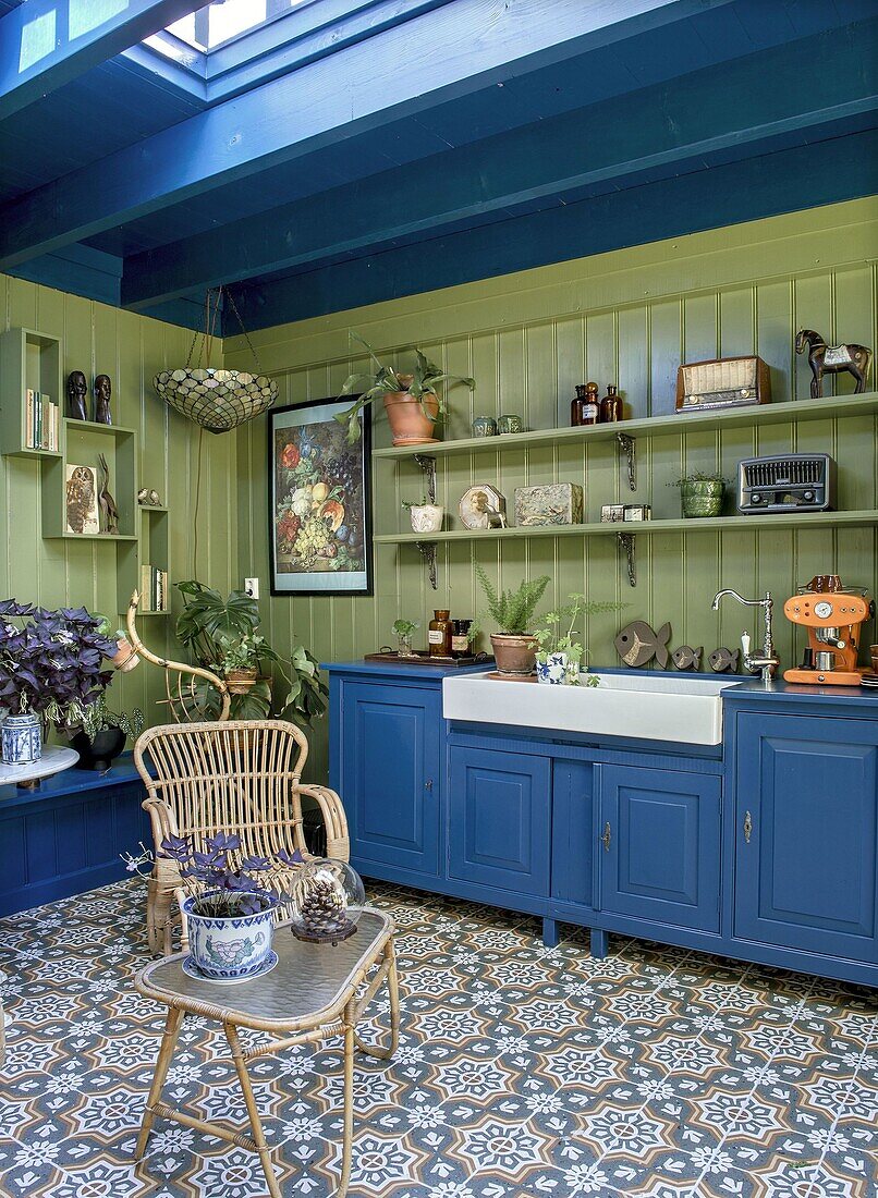 Kitchen with blue wooden cupboards, green wall and patterned floor tiles