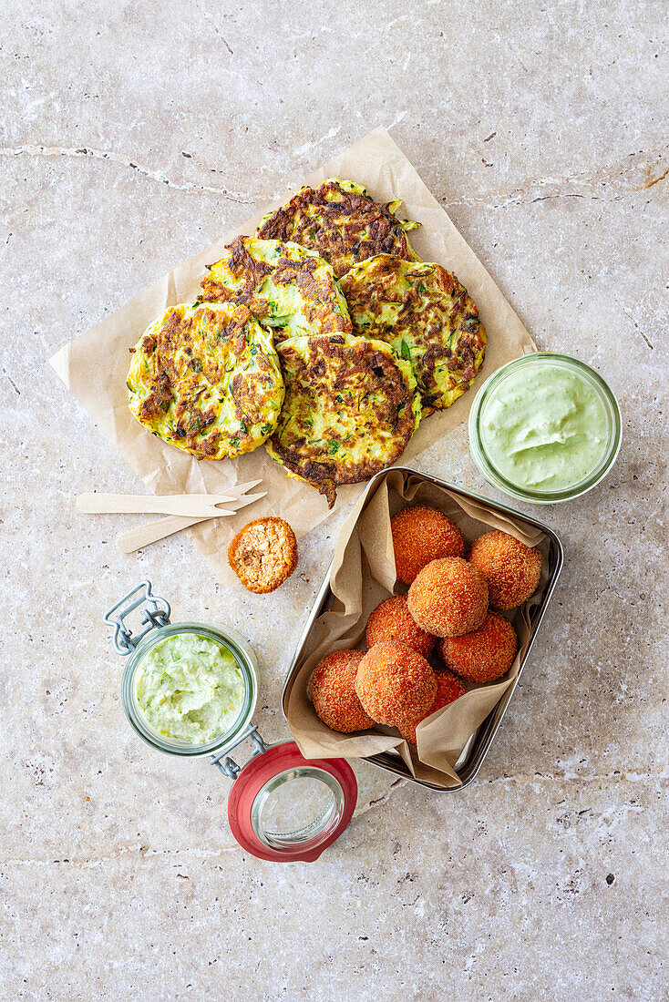 Zucchini-Halloumi-Puffer und frittierte Tofu-Bällchen mit Avocado-Frischkäse-Creme