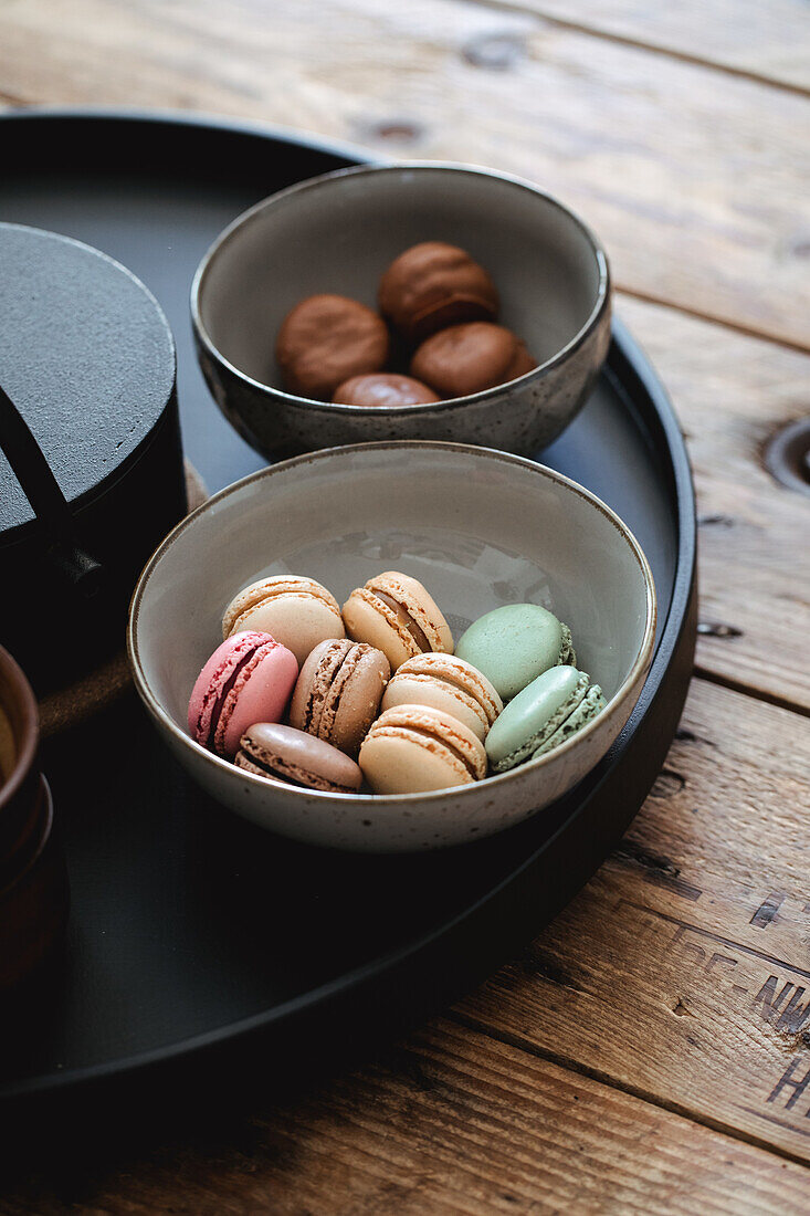 Macarons in pastel colours in a ceramic bowl on a wooden table