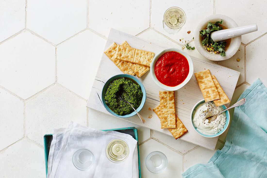 Red, white and green dips with crackers (kale pesto, tomato dip and yogurt dip)