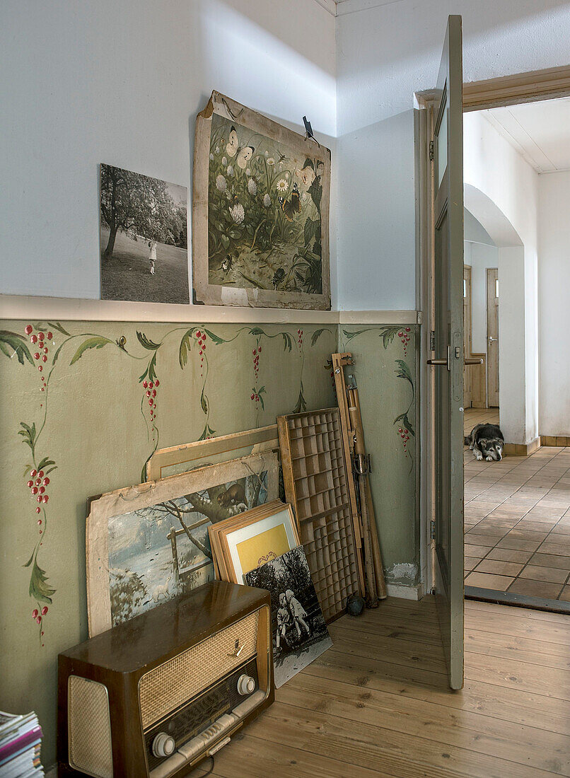 Vintage radio and framed pictures in room with floral wallpaper