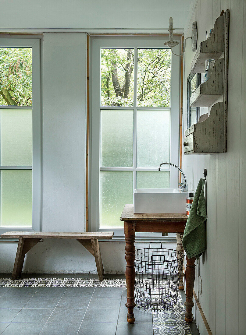 Badezimmer mit Holzbank, Vintage-Waschtisch und Fenstern mit Sichtschutz