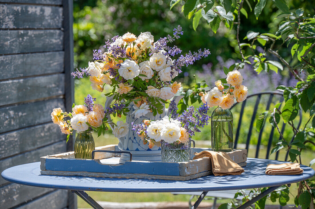 Weiße Kletterrose 'Ghislaine de Feligonde' und Katzenminze in Blumensträußen auf Gartentisch