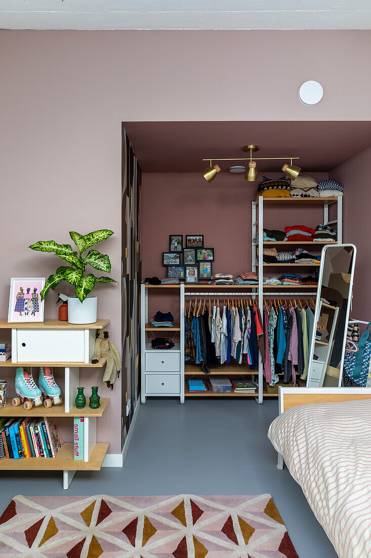 Walk-in wardrobe in a bedroom with pink walls and plant