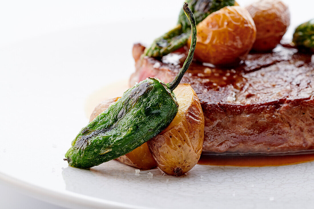 Beef steak with roast peppers, small jacket potatoes and demi-glace