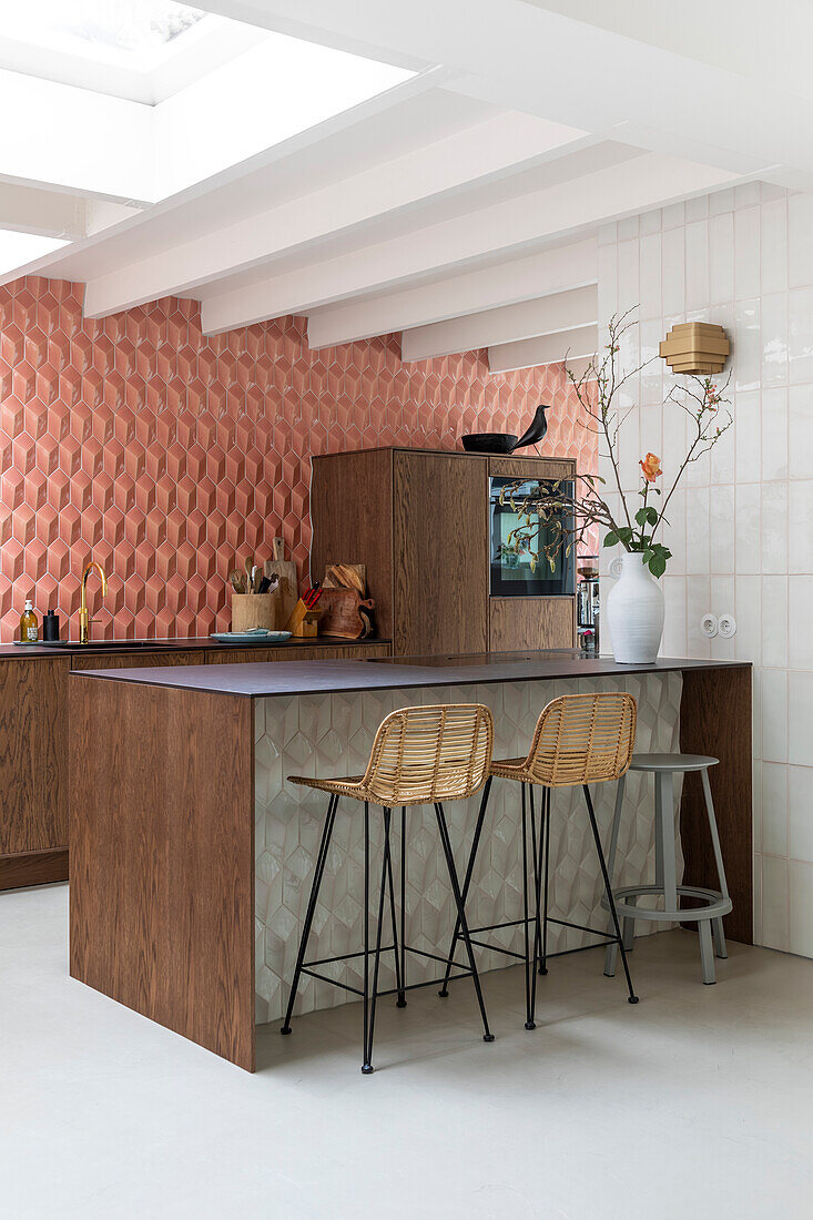 Kitchen with wood paneled island, rattan bar stools and geometric wall design