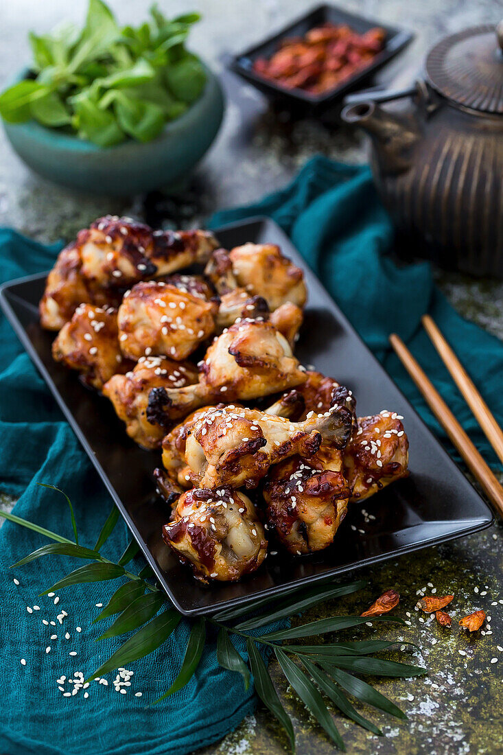 Fried glazed chicken drumsticks with sesame seeds