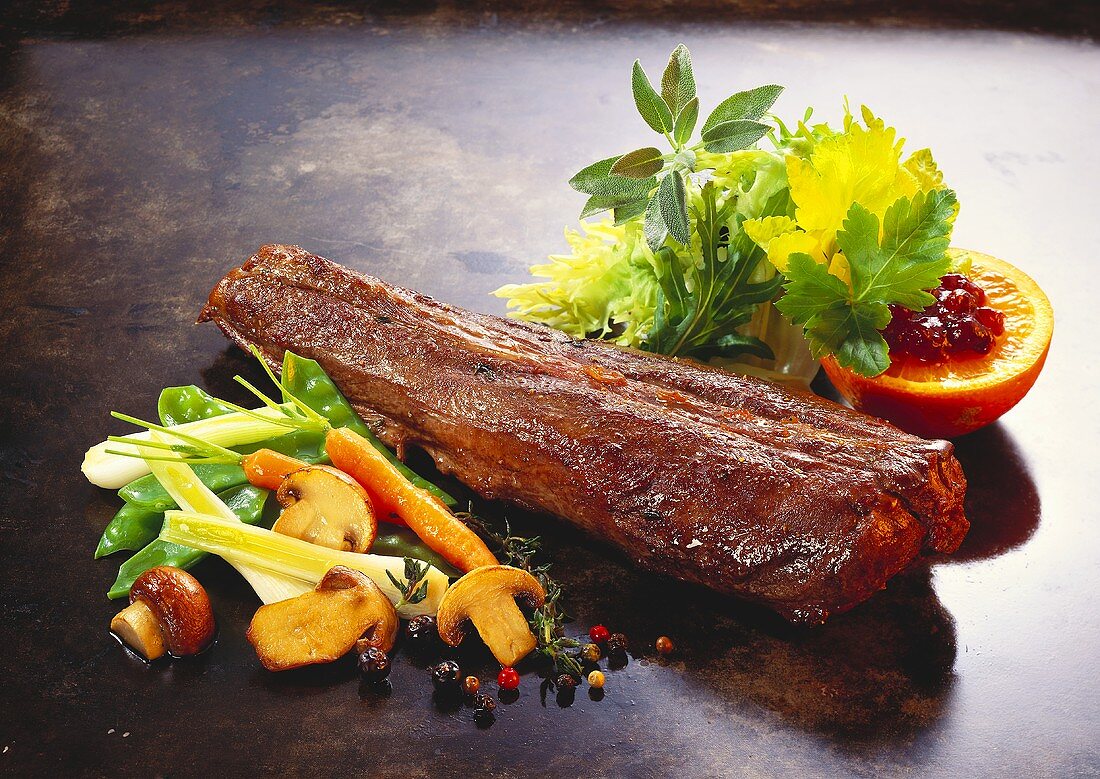 Whole hare chine with vegetables & salad on black baking tray