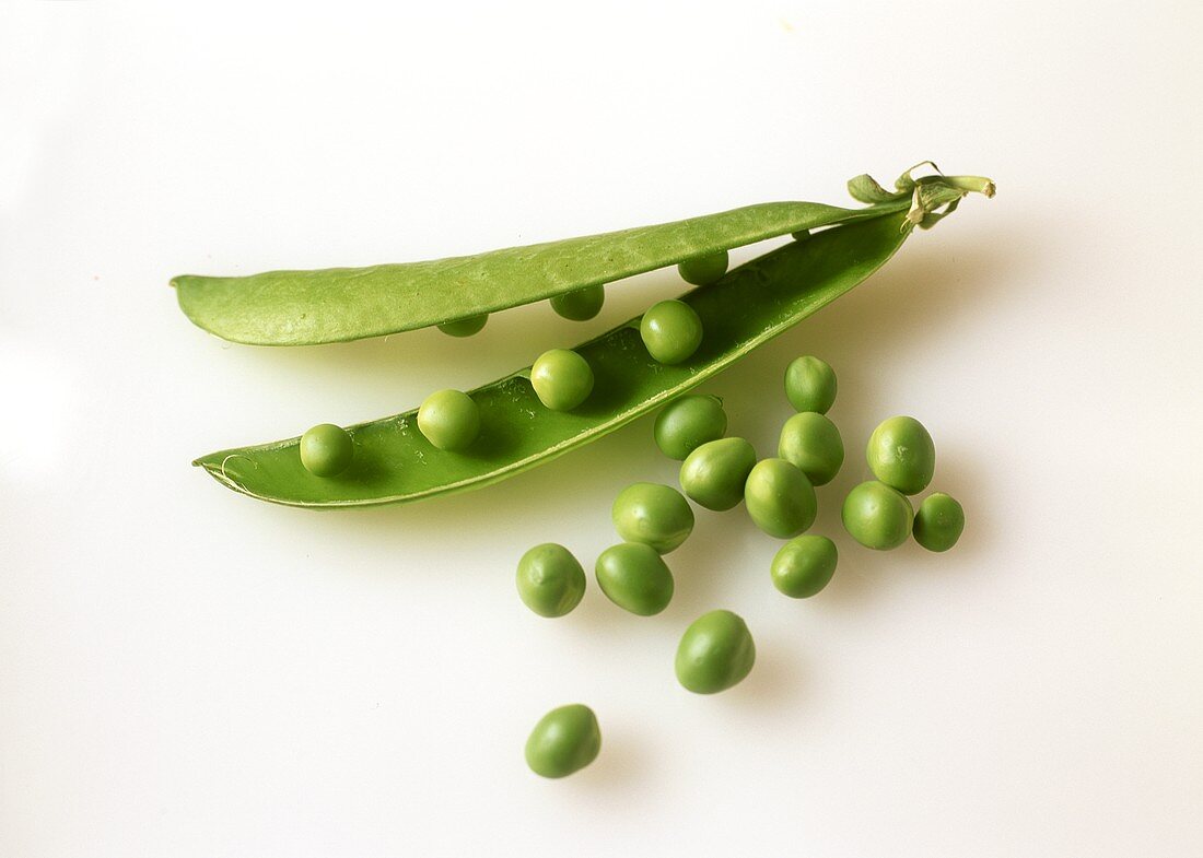 Opened pea pod with peas & a few loose peas