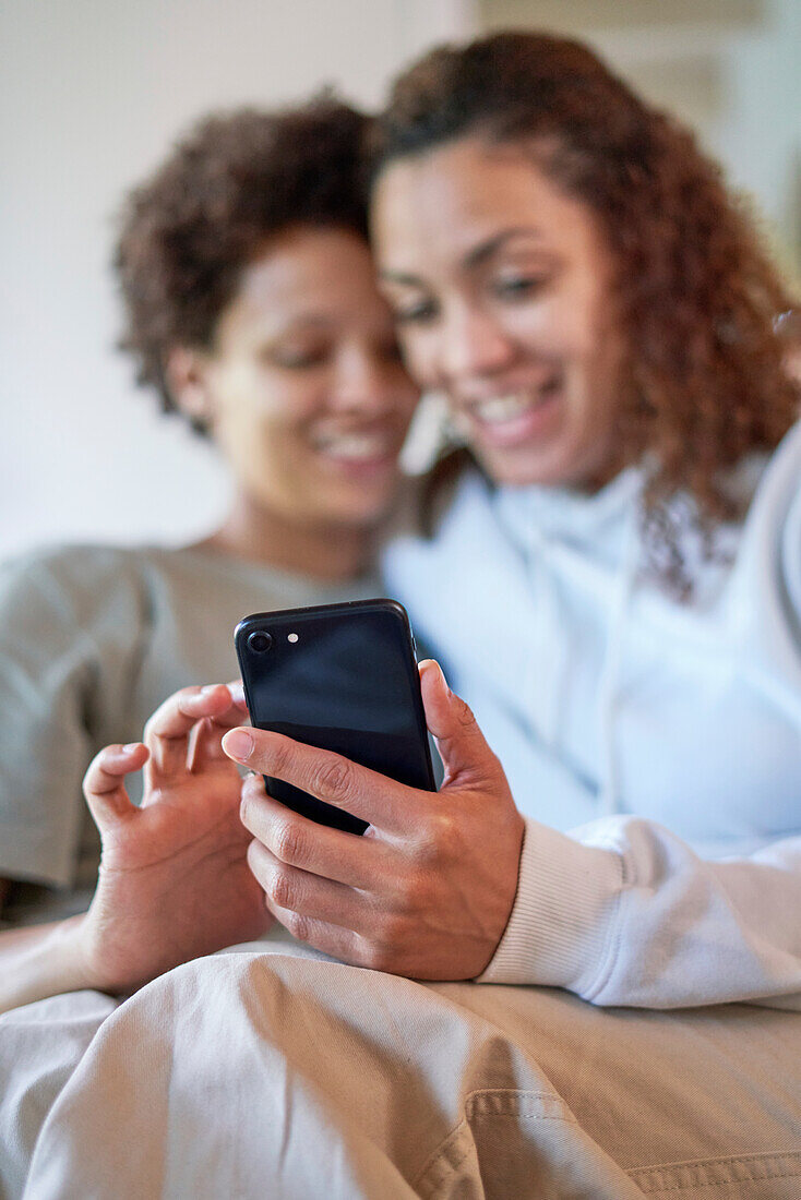 Happy lesbian couple using smart phone