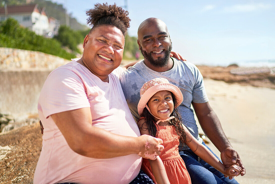 Happy gay male couple with daughter on beach