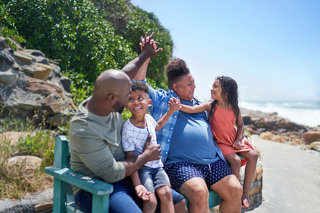 Family holding hands on beach bench