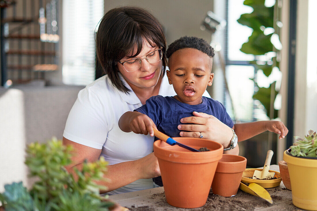 Mother and son planting plants in flowerpots