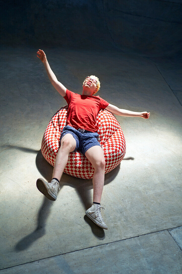 Young man falling back on bean bag chair