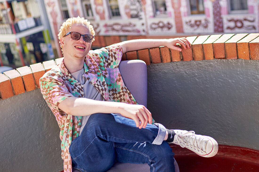 Young albino man sitting on sunny urban rooftop