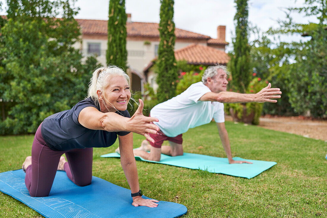 Senior couple practicing yoga in villa garden