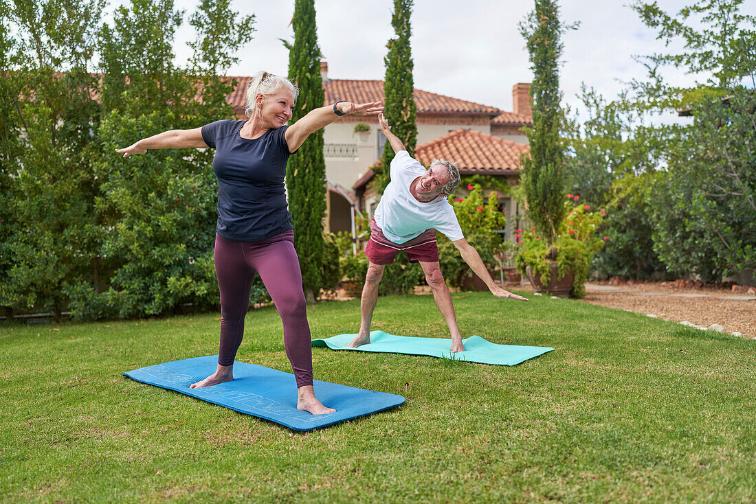 Senior couple practicing yoga in villa garden