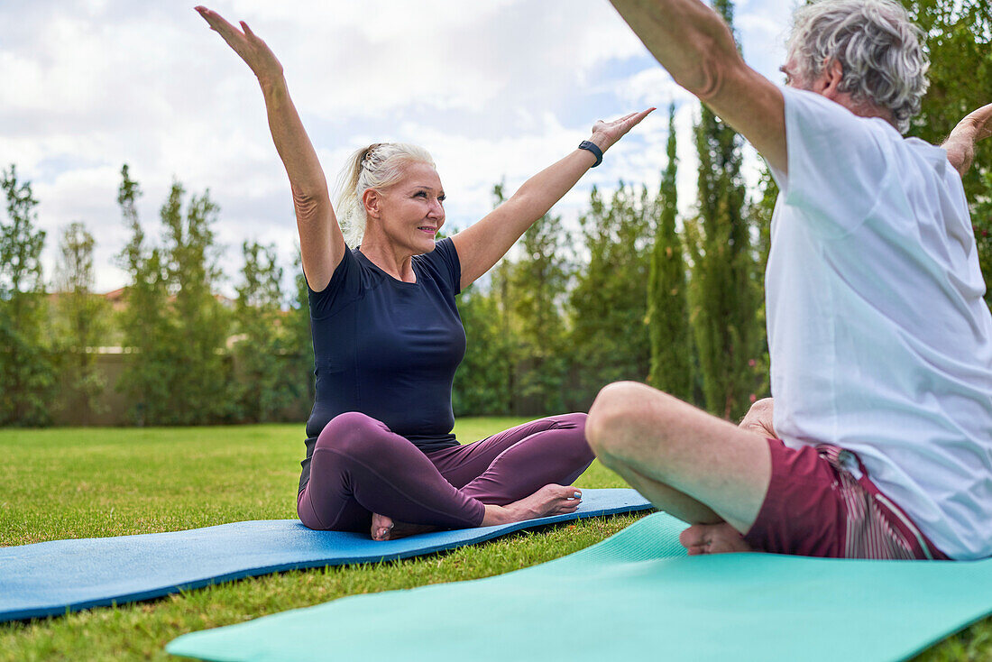 Senior couple practicing yoga together in park