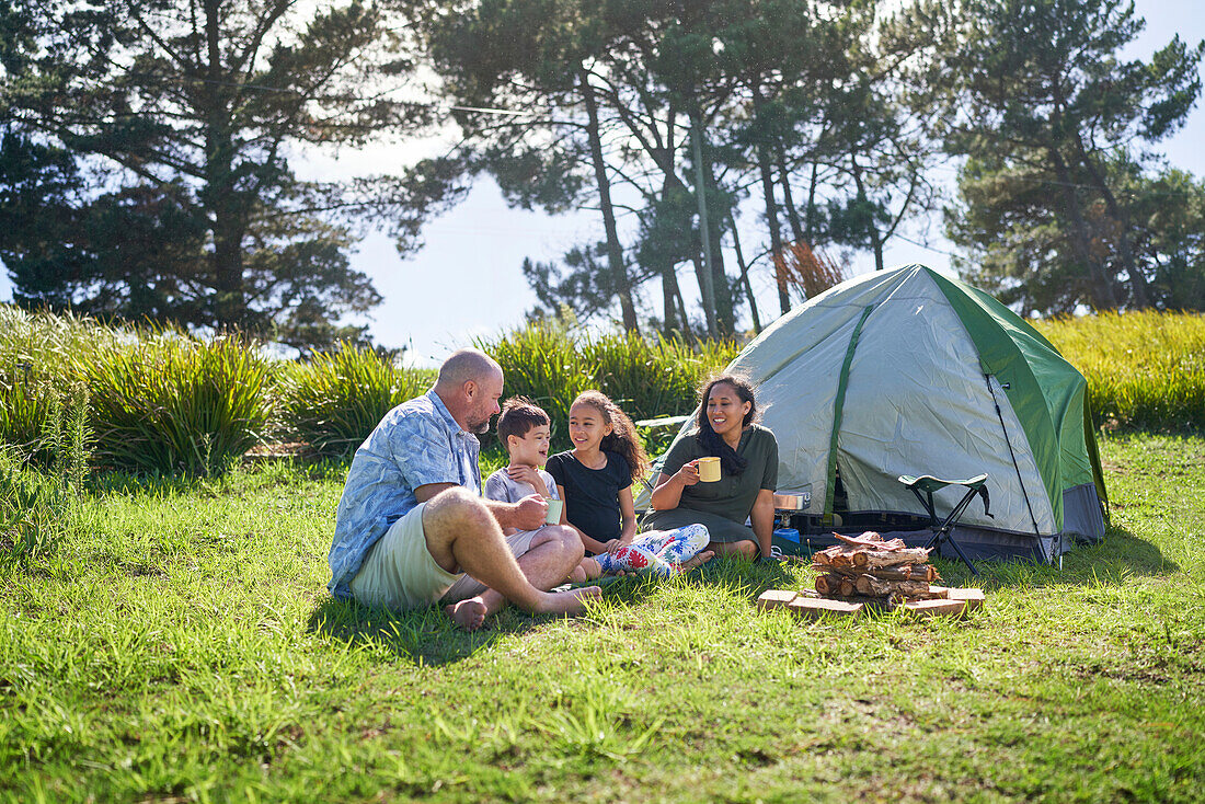 Family talking outside tent at sunny campsite